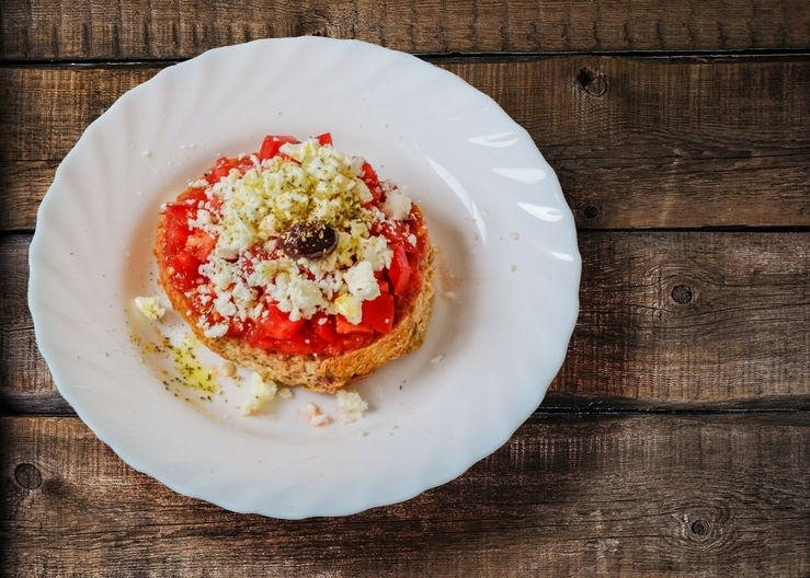 Dakos appetizer with tomato and mizithra cheese, one of the top traditional Cretan food you must try.